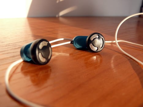 Blue earphones with wires in the brown table