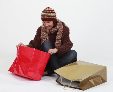 Happy young woman searching for gifts in a bag.