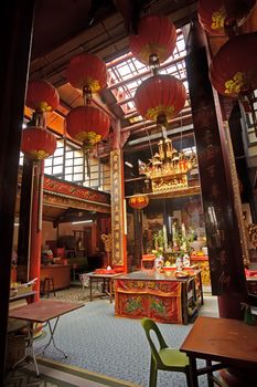 Chinese Buddhism temple interior with suspension of red lanterns and altar.