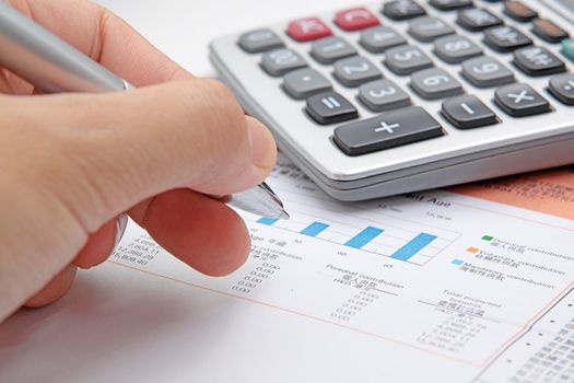 Businessman's hand showing diagram on financial report with pen. 