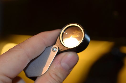 A hand holding an optic loupe.