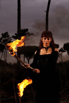 View of a dark clothed woman with a torch on her hands.