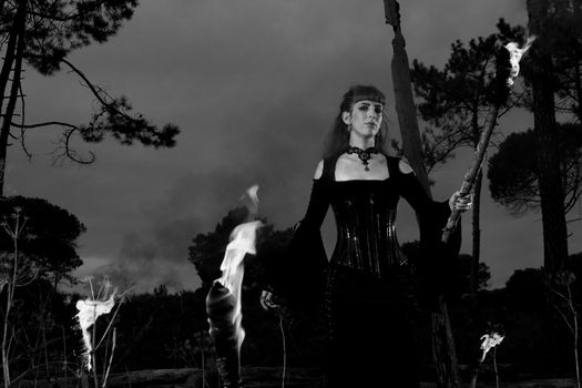 View of a dark clothed woman with a torch on her hands.