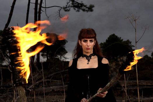 View of a dark clothed woman with a torch on her hands.