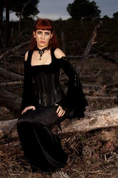 Dark gothic woman with dark clothes posing on the night forest.
