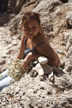 young woman builds stone stacks on the rock background