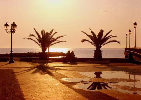 couple sitting on sea front watching sunrise