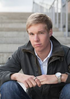 Young blond handsome chap sitting on the stairs outdoors