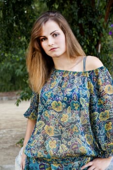 View of a beautiful girl on a floral dress on a park.