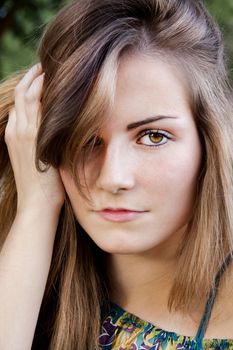 Closeup of the face of a beautiful young girl with hand on the hair.