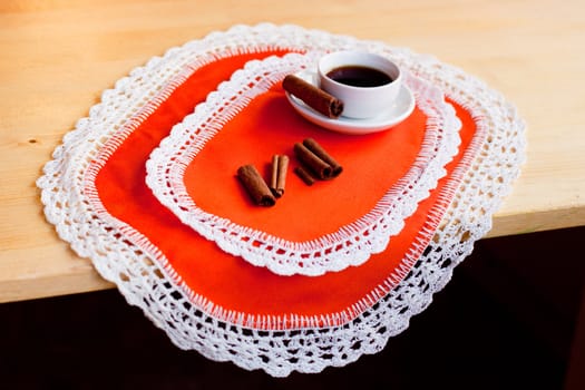 A coffee cup and several cinnamons on two orange napkins
