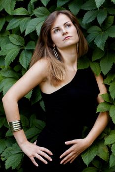 View of a beautiful girl on a black dress on a park.