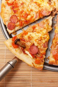 A slice of pizza is lifted from the pan with a spatula