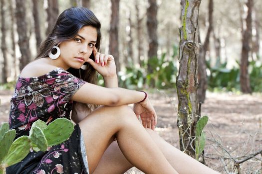 Beautiful girl with floral dress posing on a forest.