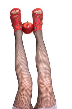  female legs in red shoes keep apple isolated on white background