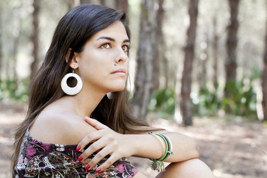 Beautiful girl with floral dress posing on a forest.