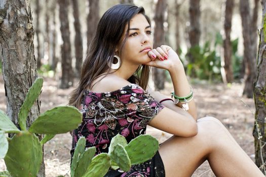 Beautiful girl with floral dress posing on a forest.
