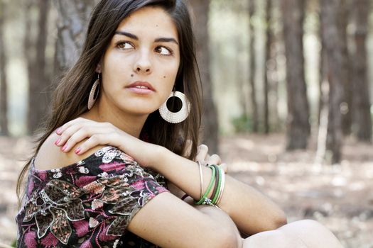 Beautiful girl with floral dress posing on a forest.