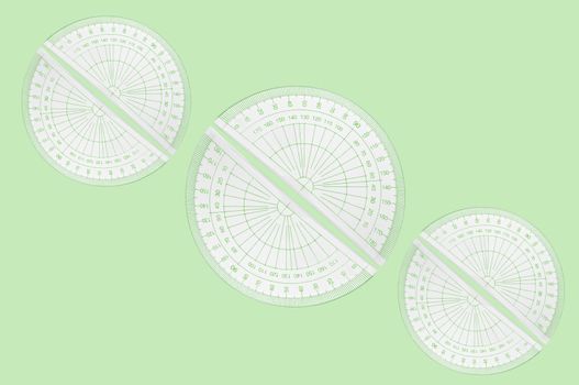 Several plastic protractors arranged in formation over pale green background.