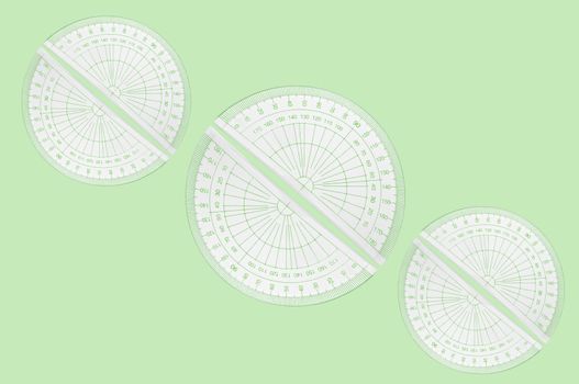 Several plastic protractors arranged in formation over pale green background.