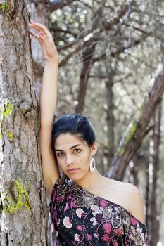 Beautiful girl with floral dress posing on a forest.