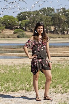 Beautiful girl with floral dress posing on a forest with lots of birds.
