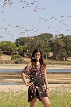 Beautiful girl with floral dress posing on a forest with lots of birds.