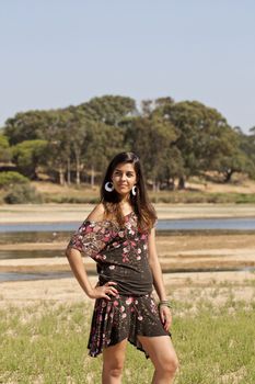 Beautiful girl with floral dress posing on a lake.