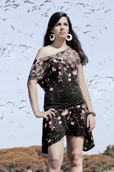 Beautiful girl with floral dress posing on a forest with lots of birds.