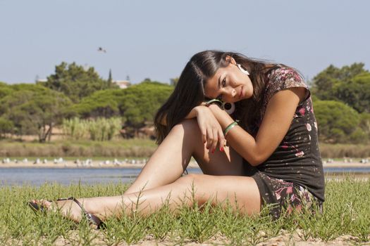 Beautiful girl with floral dress posing on a lake.