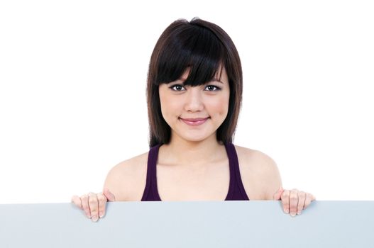 Portrait of a cute young woman holding blank billboard over white background.