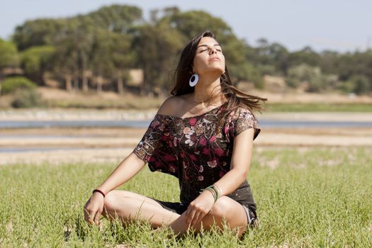 Beautiful girl with floral dress meditating on the nature.
