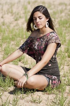 Beautiful girl with floral dress meditating on the nature.