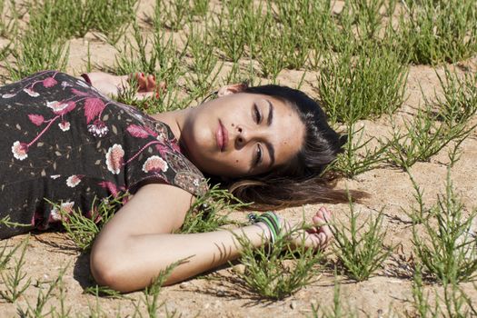 Beautiful girl with floral dress sleeping on the nature.