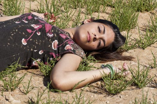 Beautiful girl with floral dress on the ground in a sunny day.