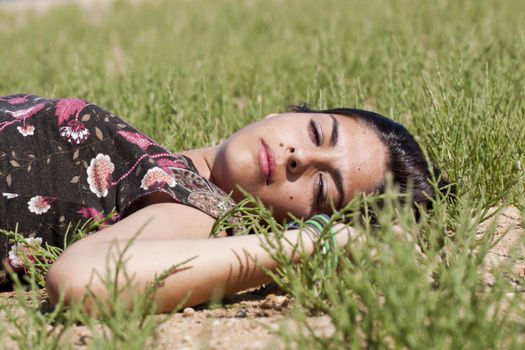 Beautiful girl with floral dress on the ground in a sunny day.