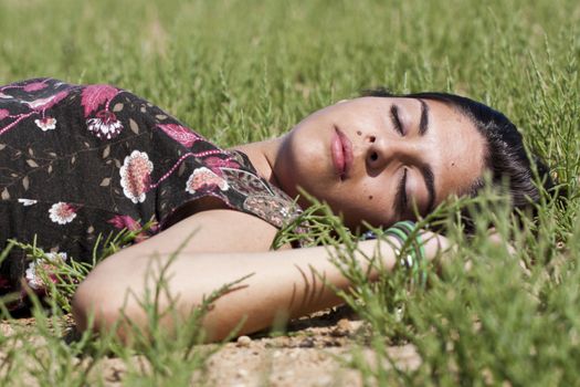 Beautiful girl with floral dress sleeping on the nature.