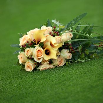 Bouquet of yellow callas and roses on a green lawn
