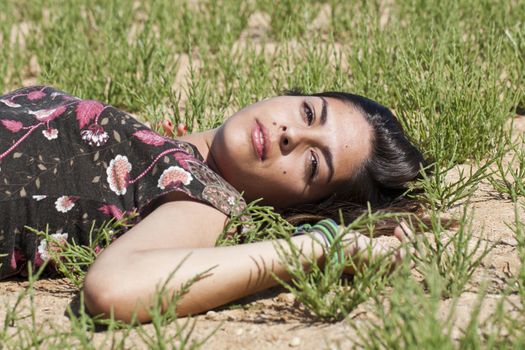Beautiful girl with floral dress on the ground in a sunny day.
