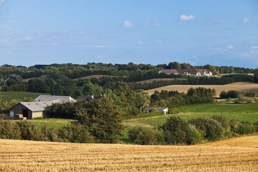 country landscape with farm buildings, fields, trees and hills