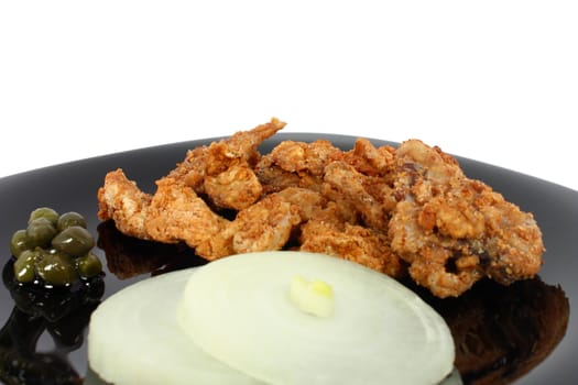 Pork greaves on black plate isolated on white