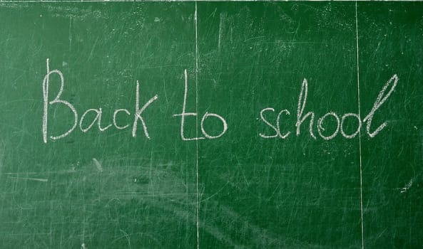 Green chalk blackboard written Back To School with white chalk