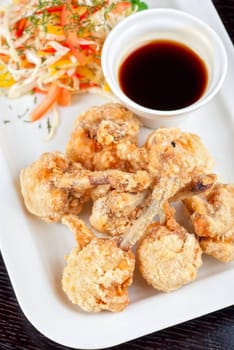 Fried chicken wings garnished with fresh vegetables with Teriyaki sauce