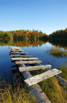 Beautiful seasonal landscape: old wooden pier on a calm lake in the fall.