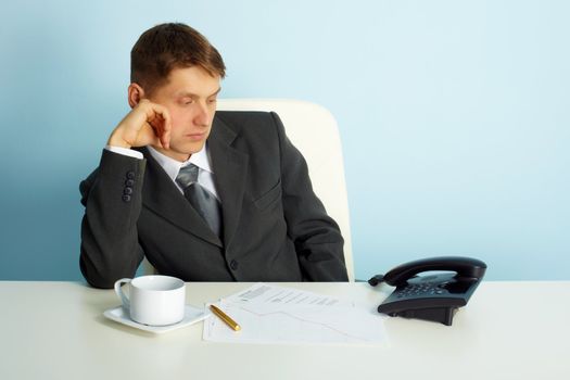 thoughtful man in the office looks at the phone
