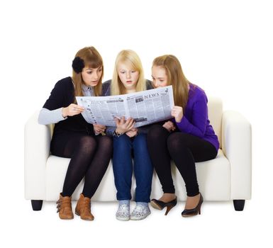 Three girlfriends teen read with interest newspaper sitting on the couch