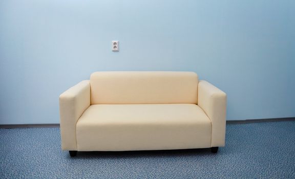 One white sofa near the blue wall