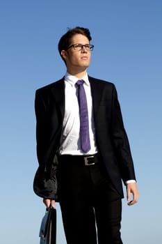 View of a bunisess man in a dark suit walking with briefcase.
