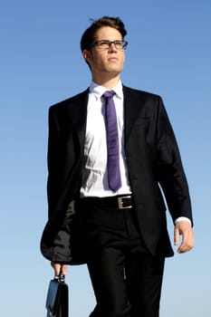 View of a bunisess man in a dark suit walking with briefcase.