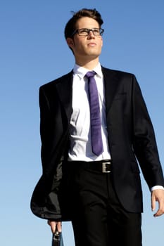 View of a young business man walking down the beach.